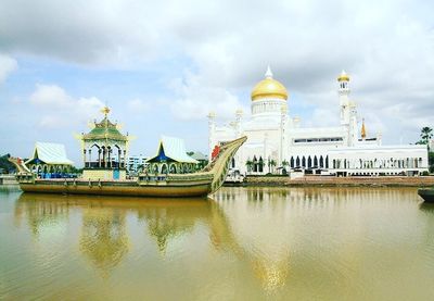 View of temple in water against cloudy sky