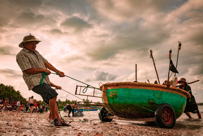 Fishing boat moored on beach against sky during sunset