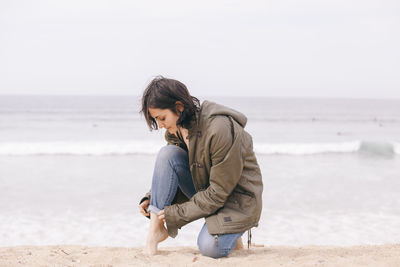 Full length of woman crouching on sand at beach