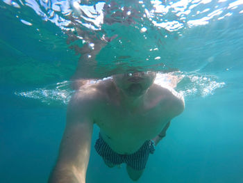 Shirtless man swimming in adriatic sea on sunny day