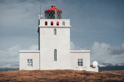 Lighthouse on field against sky