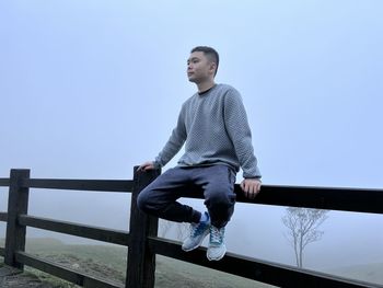 Portrait of young man standing against clear sky