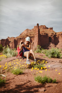 Hiker takes off backpack to rest under red sandstone towers