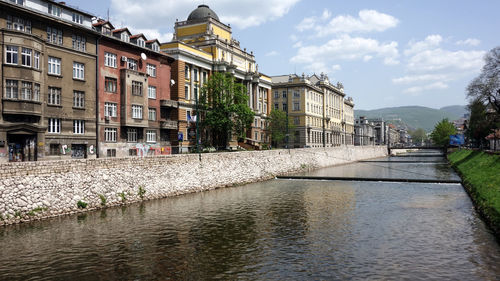 River by buildings in city against sky