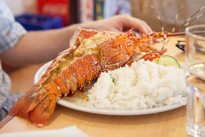Midsection of man having seafood and rice in restaurant