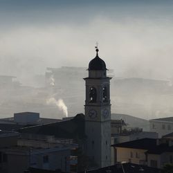 View of clock tower in city against cloudy sky
