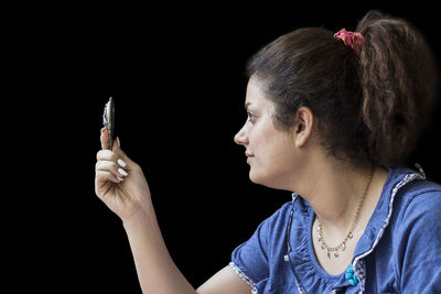 Close-up portrait of woman against black background