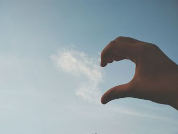 Low angle view of human hand against sky