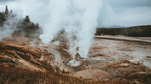 Smoke emitting from volcanic landscape against sky