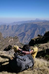 Man relaxing on field against mountains