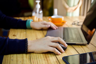 Midsection of woman using laptop on table