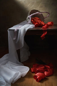 Still life with a white cloth and an overturned basket of red ribbons