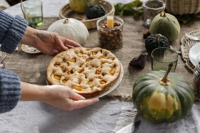 Hands of woman picking up plate with homemade pumpkin pie