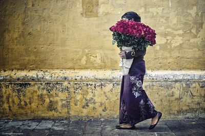 Woman with bouquet walking on street