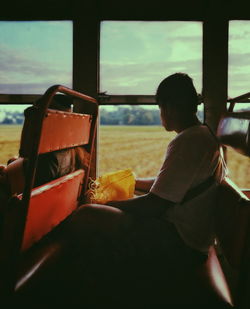 Rear view of man sitting at glass window