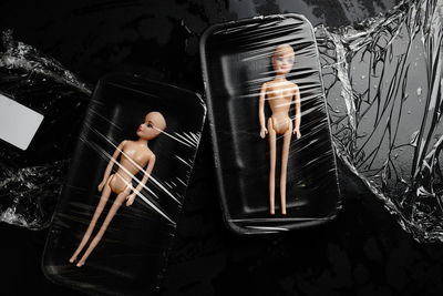 High angle view of wrapped plastic dolls wrapped in container on table