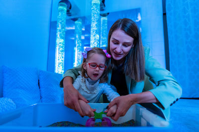 Child living with cerebral palsy interacting with her therapist during therapy session.