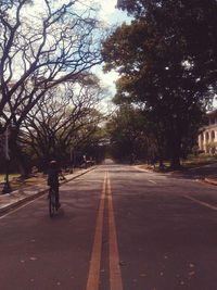 Man walking on road amidst trees against sky