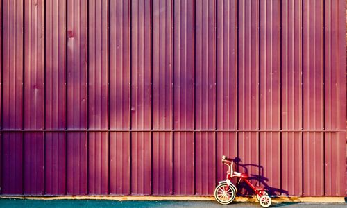 Tricycle parked on road by wall