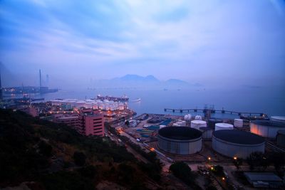 High angle view of illuminated city by sea against sky