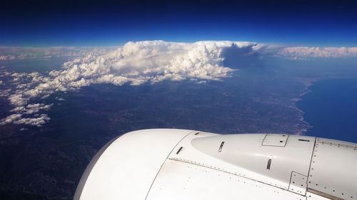 Aerial view of airplane flying over sea against sky