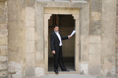 Portrait of businessman holding document while standing at doorway