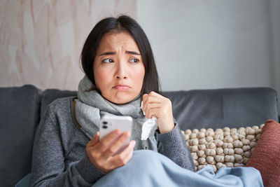 Portrait of young woman sitting on sofa at home