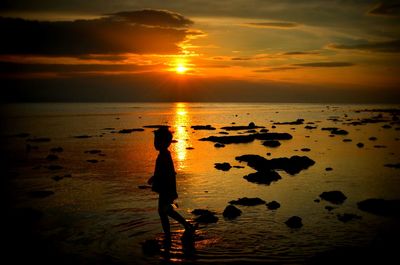 Silhouette person standing at beach during sunset