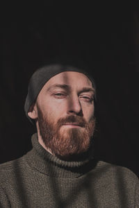 Portrait of man wearing hat against black background