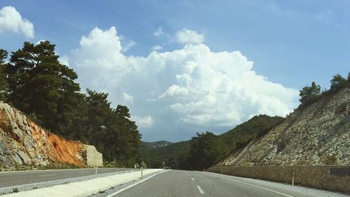 Road by mountains against sky