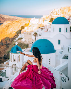 High angle view of woman sitting against built structure in city