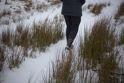 Low section of man walking on snow