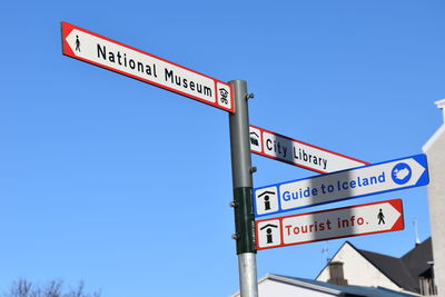 Low angle view of road signs against clear blue sky