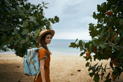 Young woman standing on tree trunk by sea