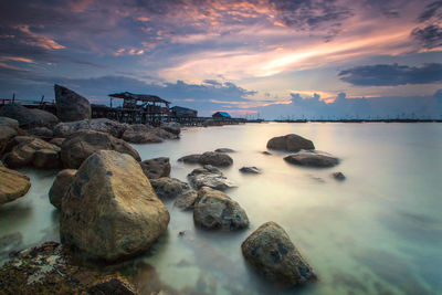 Rocks on shore against sky during sunset