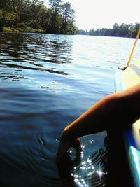 Close-up of hand against rippled lake