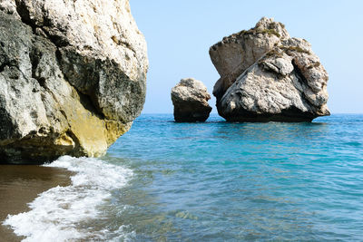 Rock formation in sea against sky