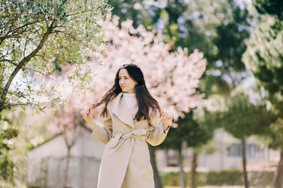 Midsection of woman standing by flowering tree