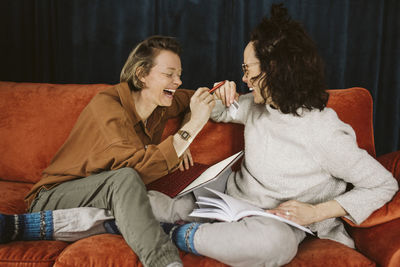 Cheerful lesbian couple sitting together on sofa at home