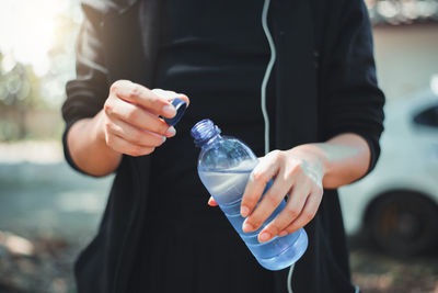 Midsection of man holding bottle while standing outdoors