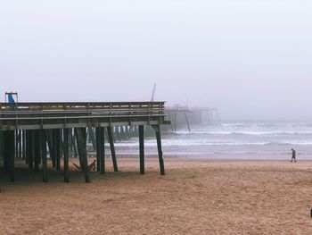 Pier on beach against clear sky