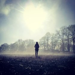 Silhouette of woman walking on field