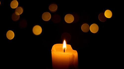 Close-up of lit candle against black background