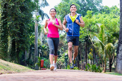 Full length of happy friends standing on footpath amidst trees