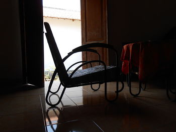 Empty chair and table in dark room by door