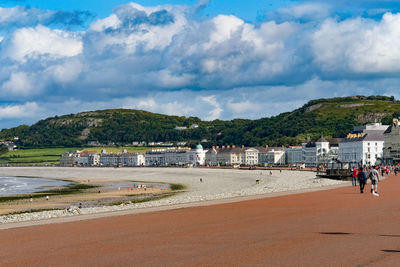 People on beach against cloudy sky