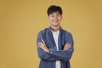 Portrait of smiling man standing against yellow background