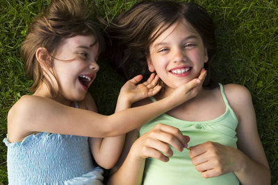 Two sisters lying in meadow having fun