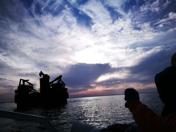 Silhouette people by sea during sunset