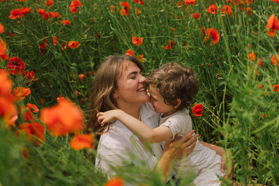 Happy mother's day. little boy and mother is playing in a beautiful field of red poppies